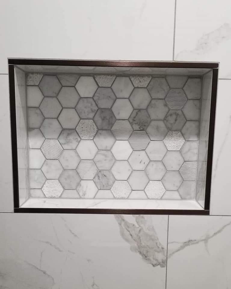 Hexagon marble mosaic shower niche framed with metal edge trim