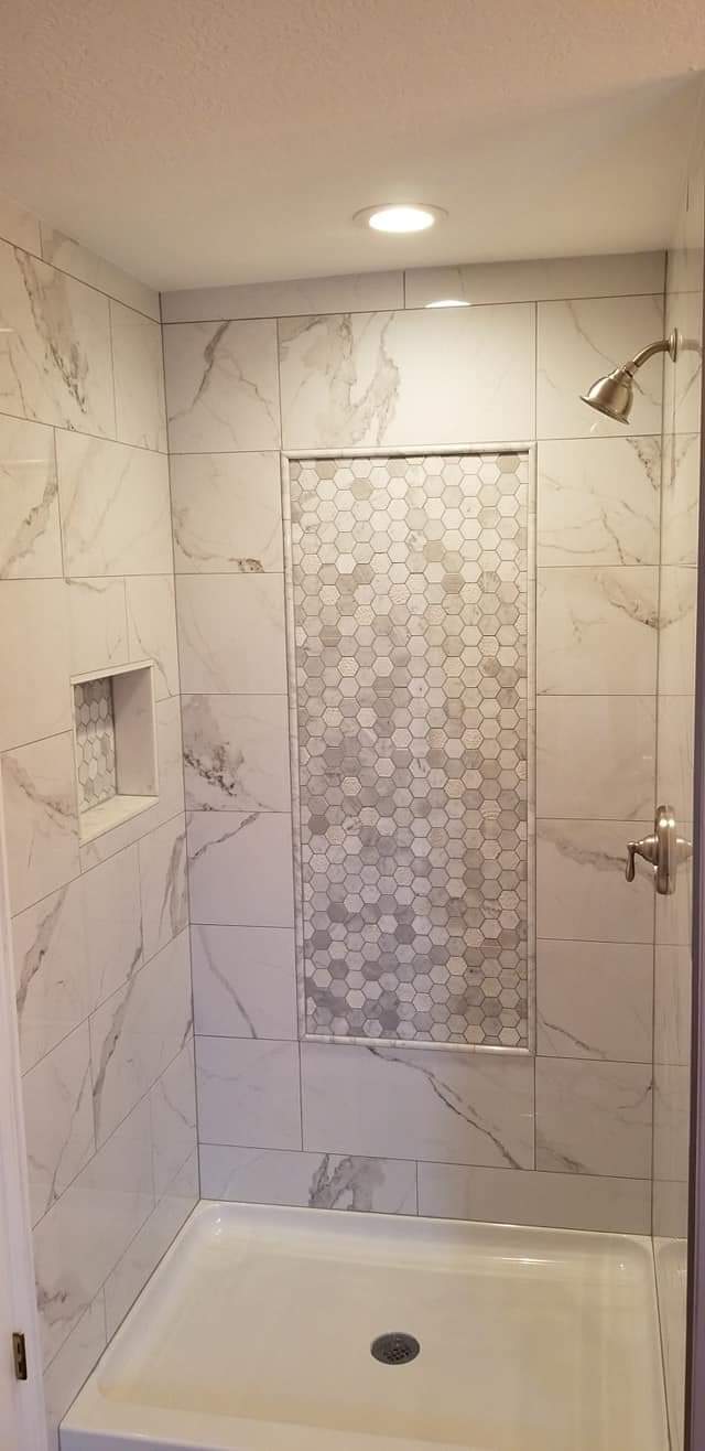 Marble look porcelain shower walls with a framed hexagon mosaic feature panel and niche