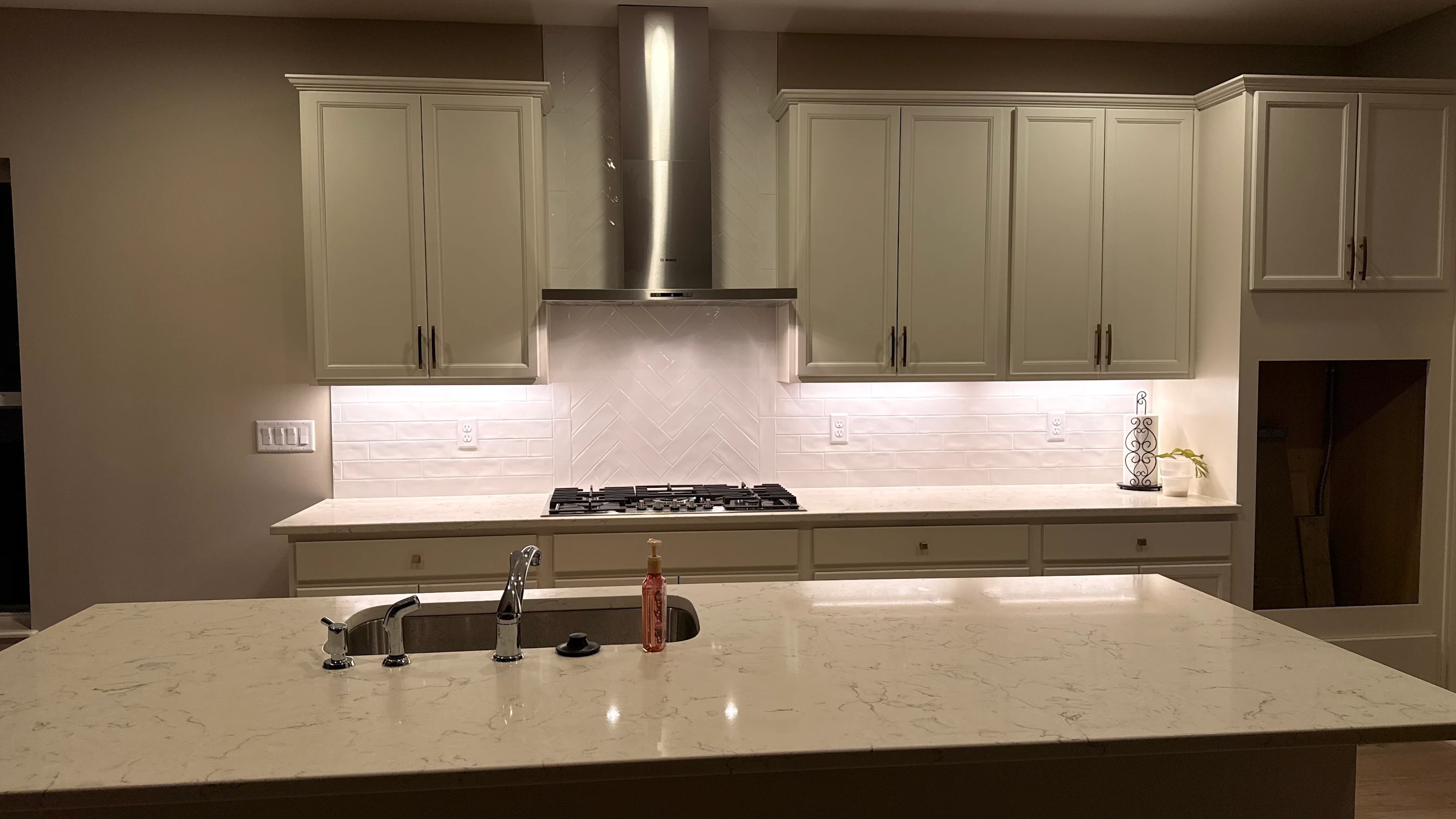 White handmade look subway tile backsplash with a herringbone feature behind the range