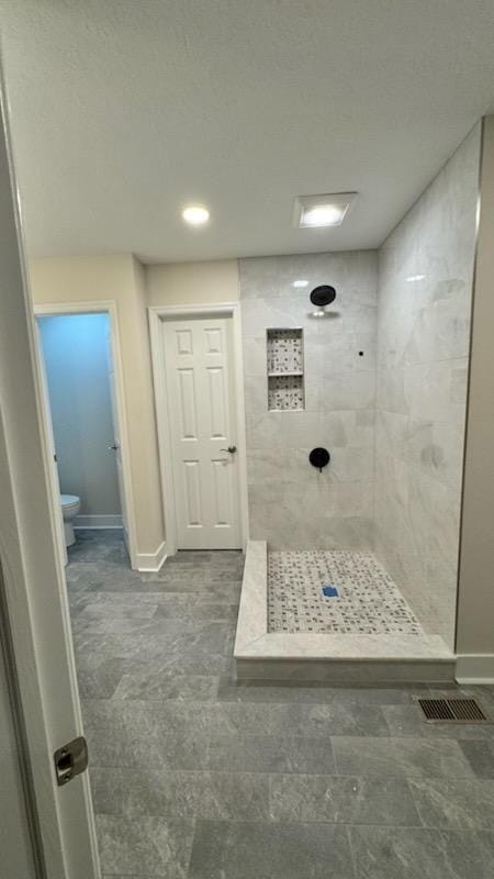 Finished tile shower with marble look walls, mosaic floor, stone curb, and plank tile bathroom floor