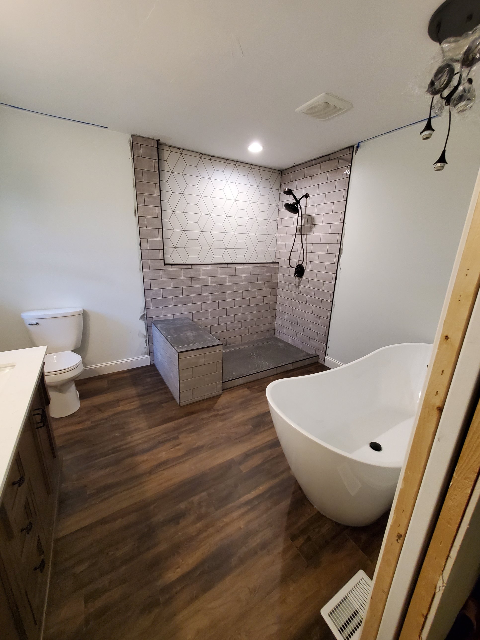Shower with tiled bench, linear drain, and geometric accent wall tile