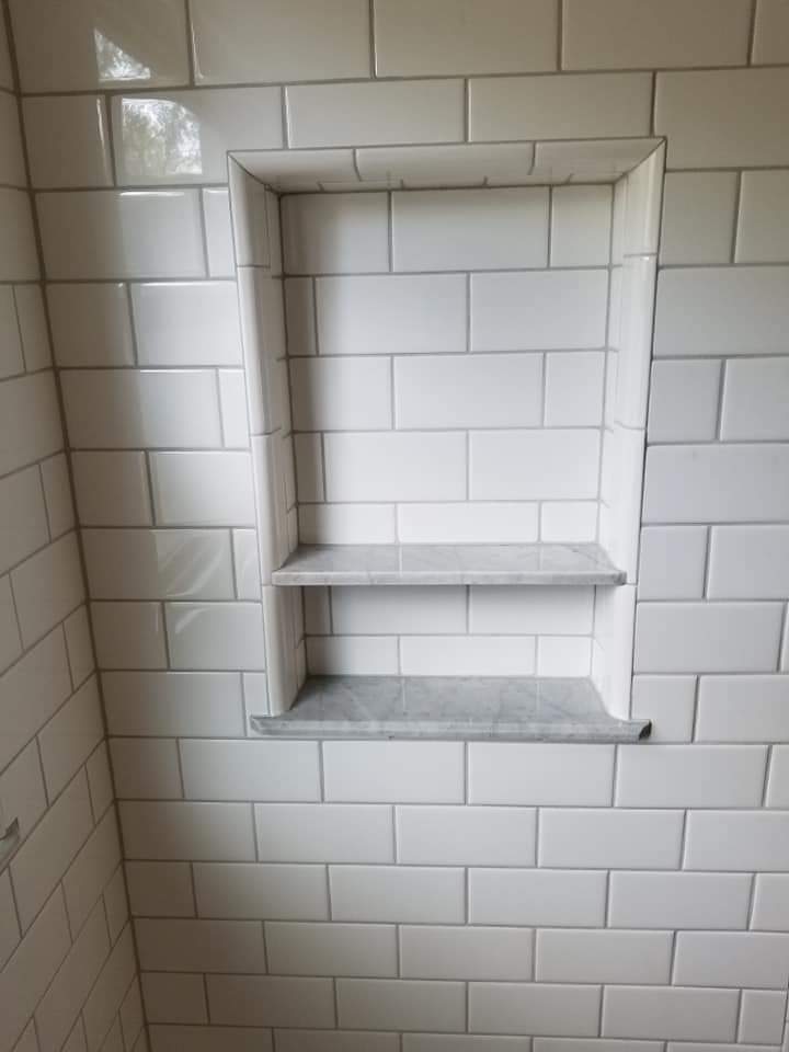 Subway tile shower niche with marble shelves