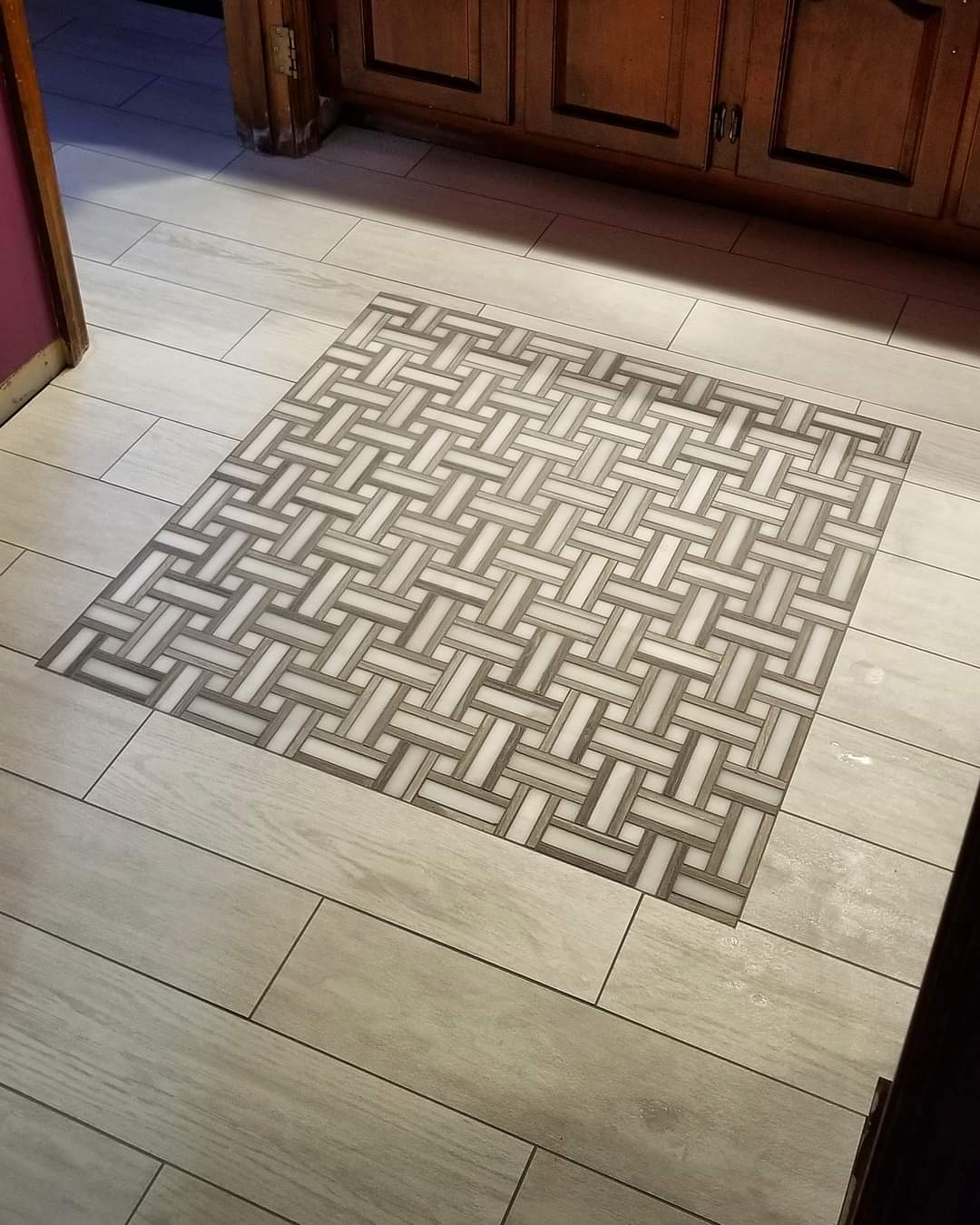 Basketweave mosaic inlay set into a wood look plank tile floor